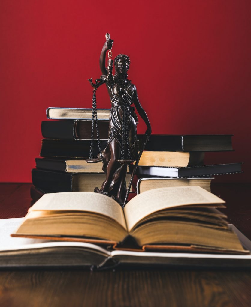 opened juridical books with lady justice statue on wooden table, law concept